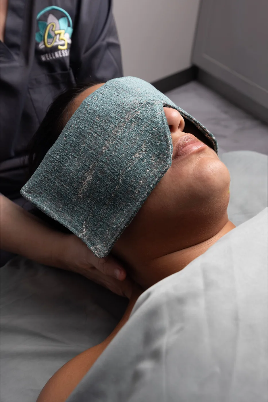 A client resting with a warm eye compress at C3 Wellness Spa, Raleigh
